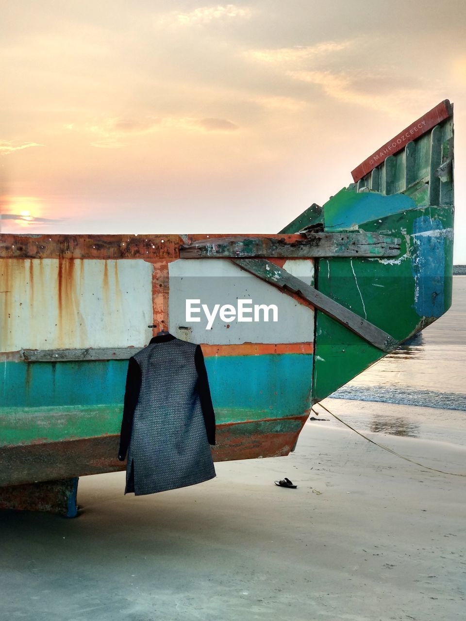 Boat moored at beach against sky during sunset