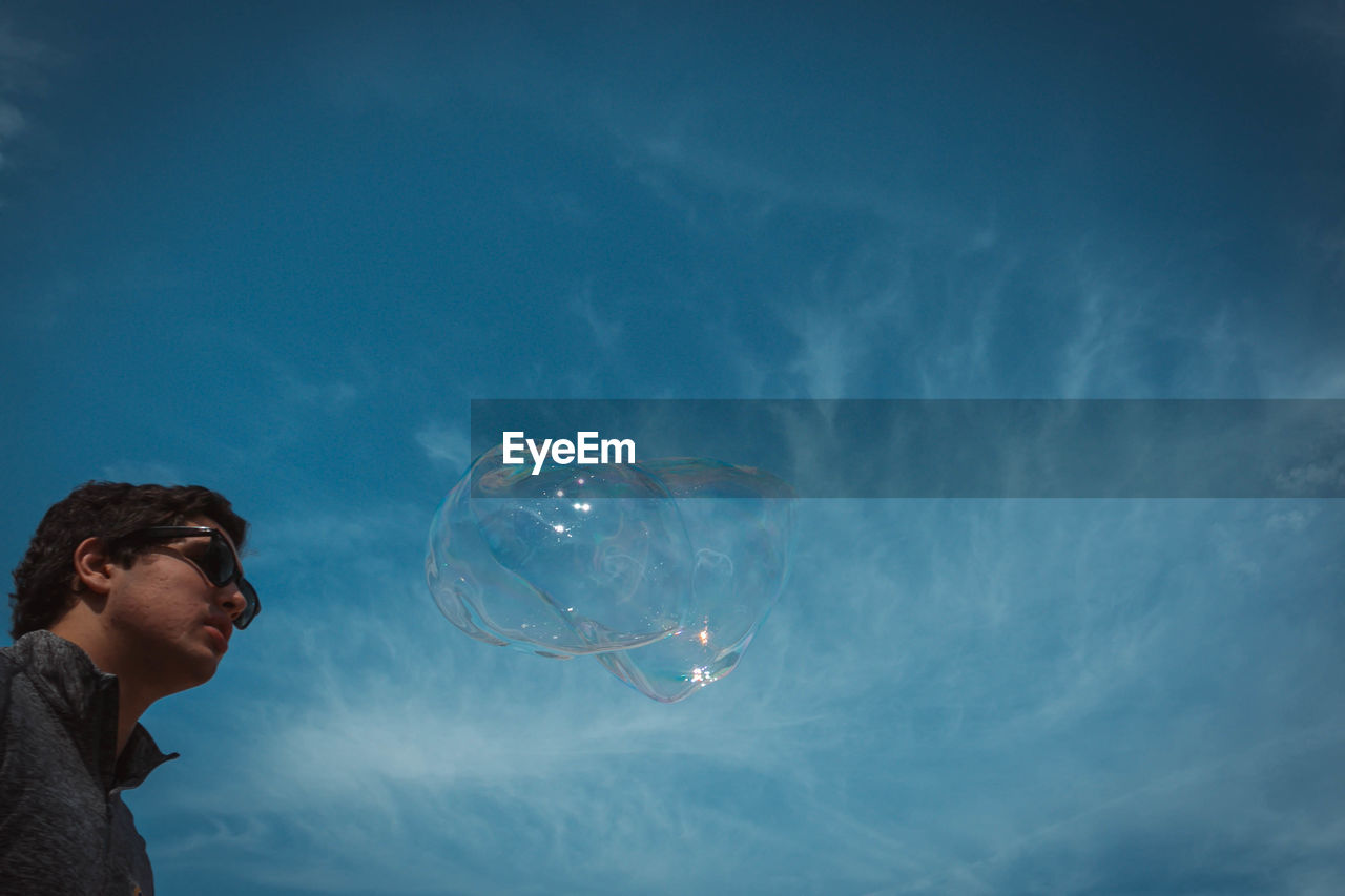 Low angle view of man by bubble against sky