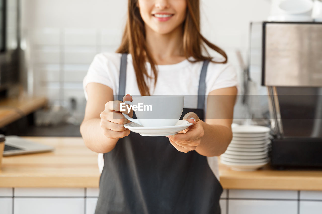 Midsection of barista holding coffee cup