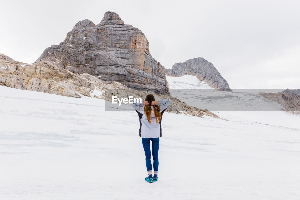 Young millennial girl enjoys the views of the alps standing on glacier