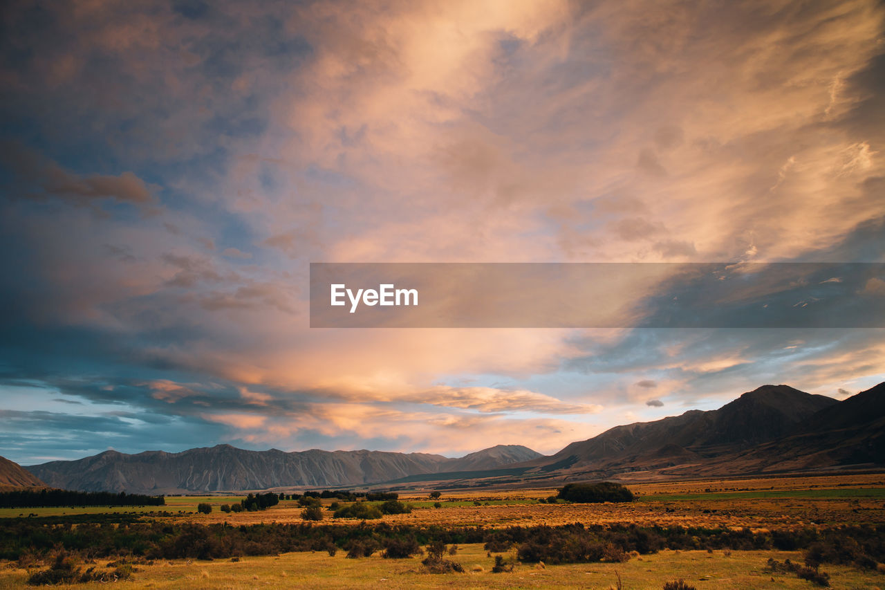 SCENIC VIEW OF LANDSCAPE AND MOUNTAINS AGAINST SKY DURING SUNSET