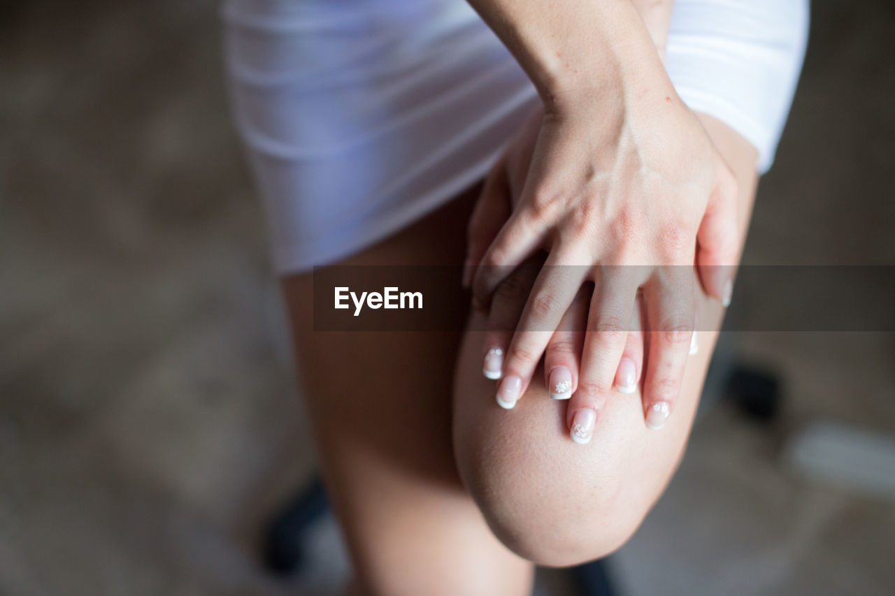 Close-up of bride hands on thigh