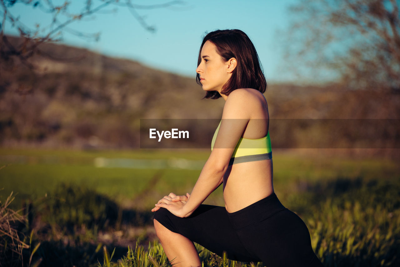 Woman exercising while standing by plants