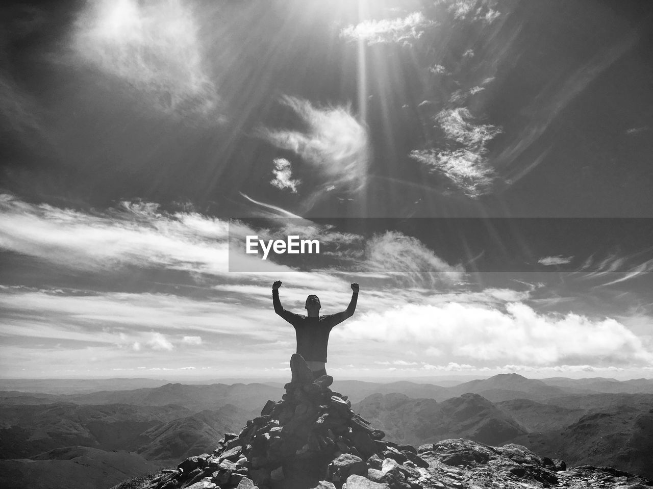 Man sitting on mountain peak against sky