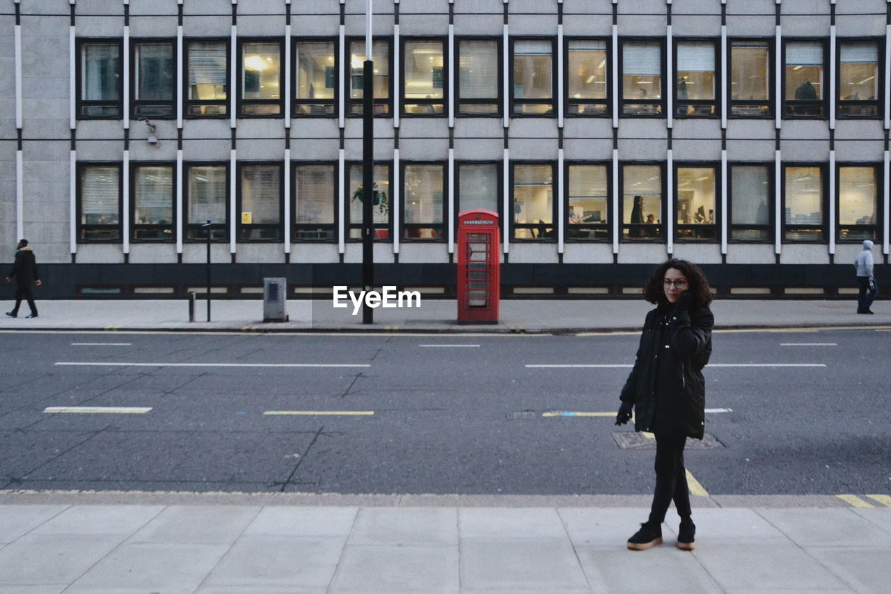 Full length of woman walking on sidewalk in city