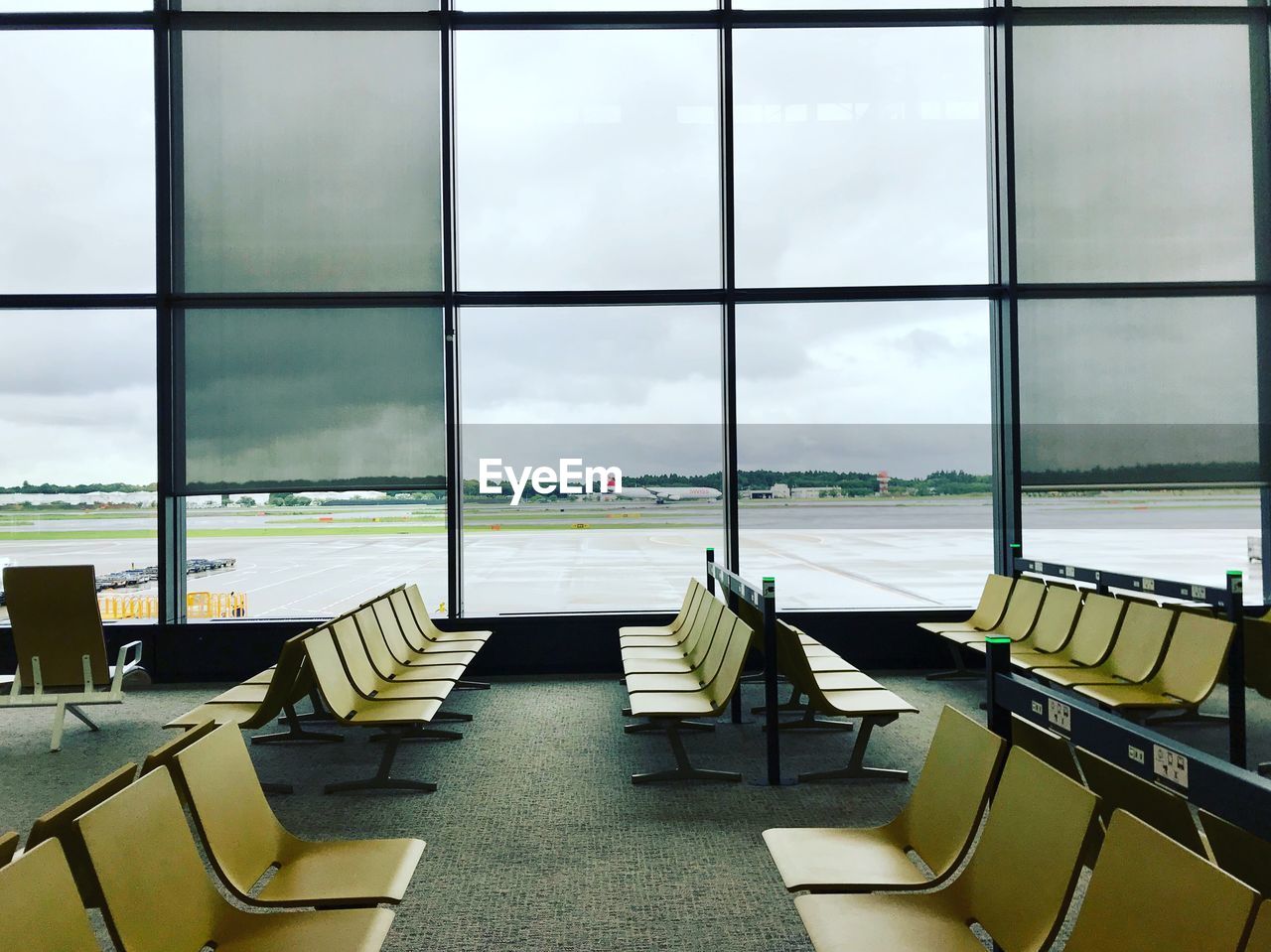 Empty chairs against sky seen through glass window