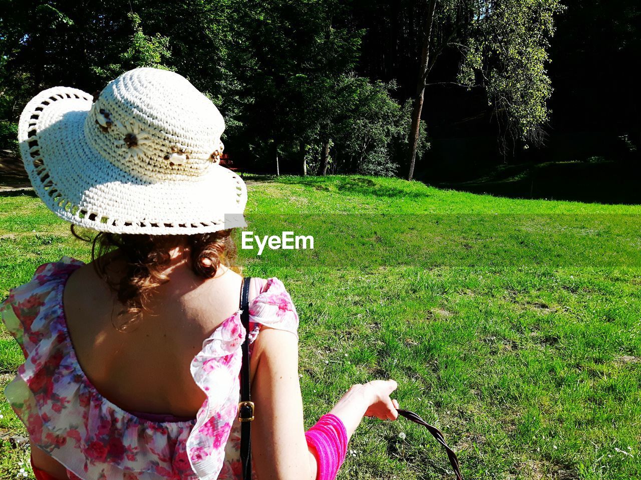 REAR VIEW OF YOUNG WOMAN SITTING ON GRASS