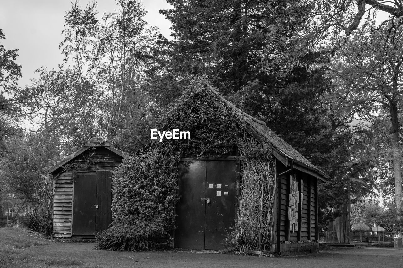 Built structure by trees and building against sky