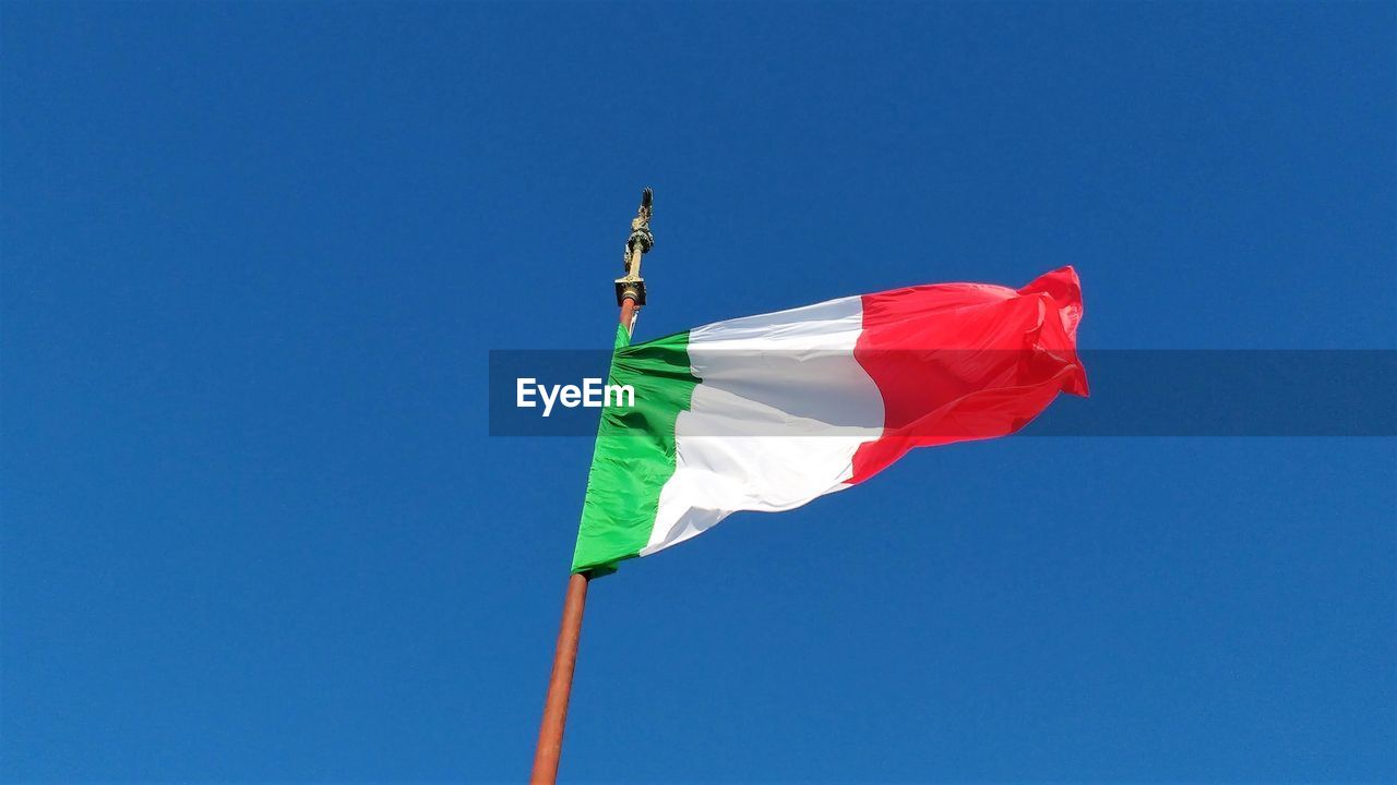 Low angle view of flag against clear blue sky