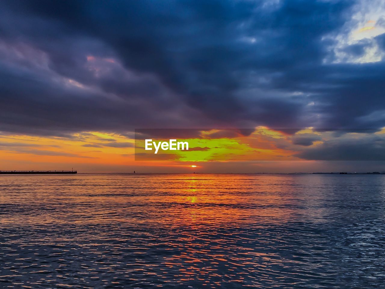 SEA AGAINST DRAMATIC SKY DURING SUNSET