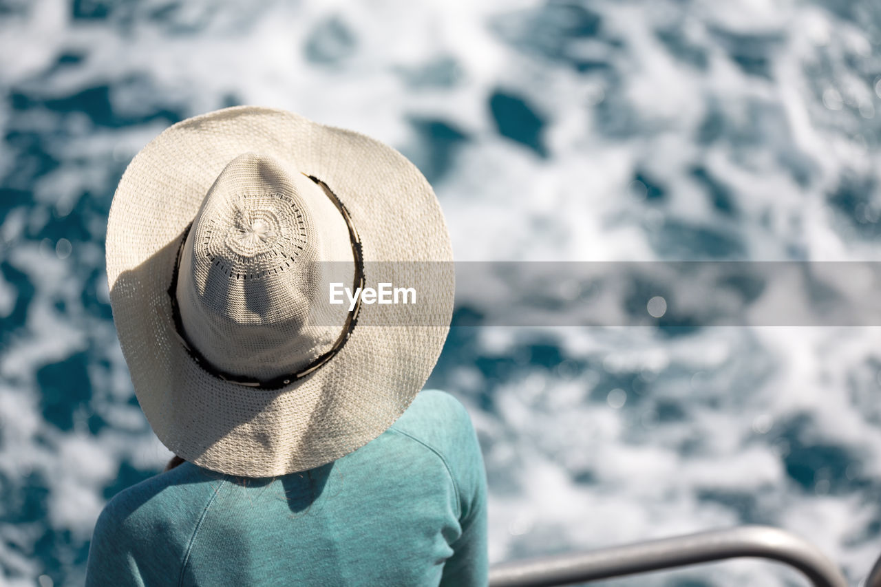 Rear view of woman wearing hat while standing by railing