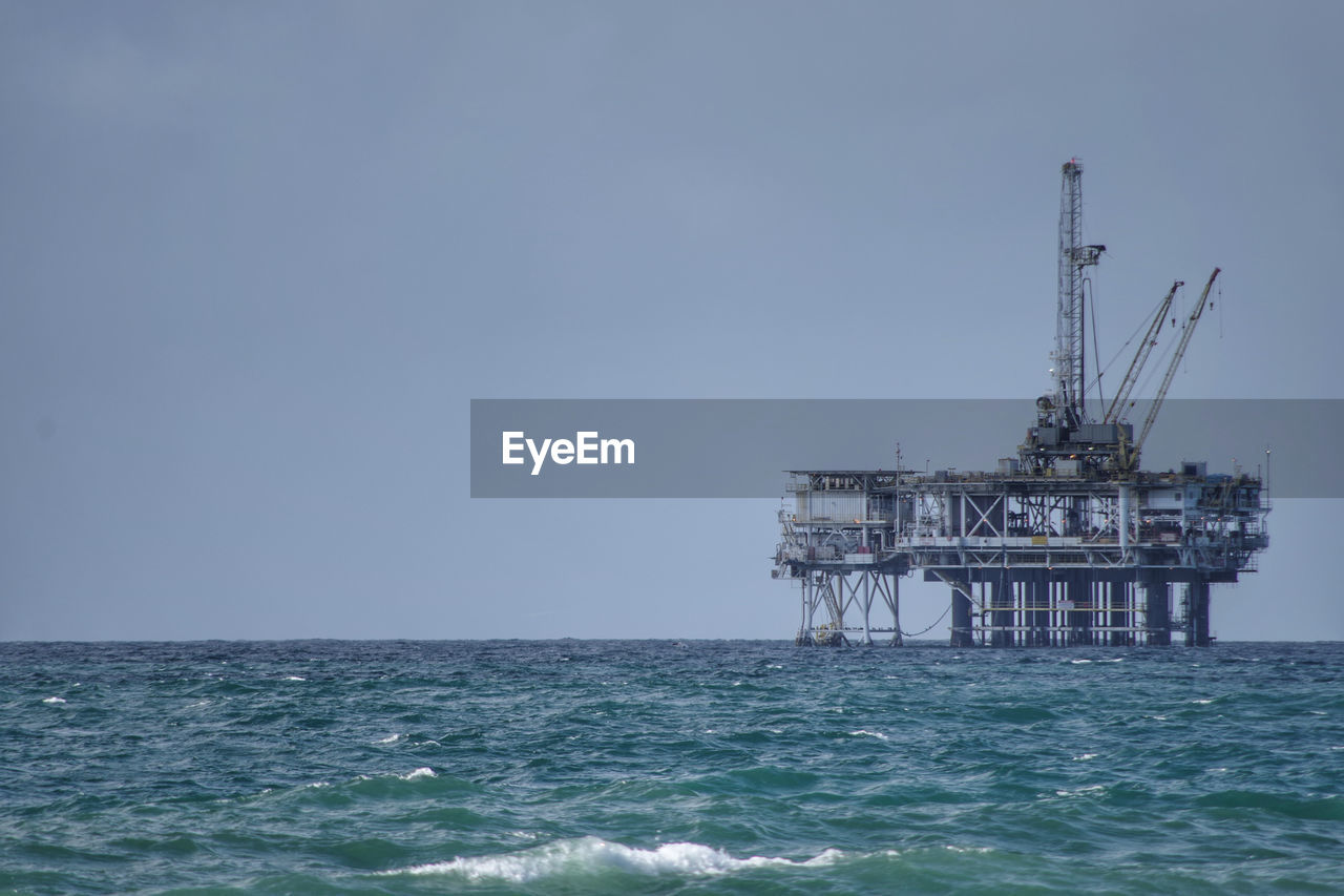 Scenic view of oil platform in sea against clear sky