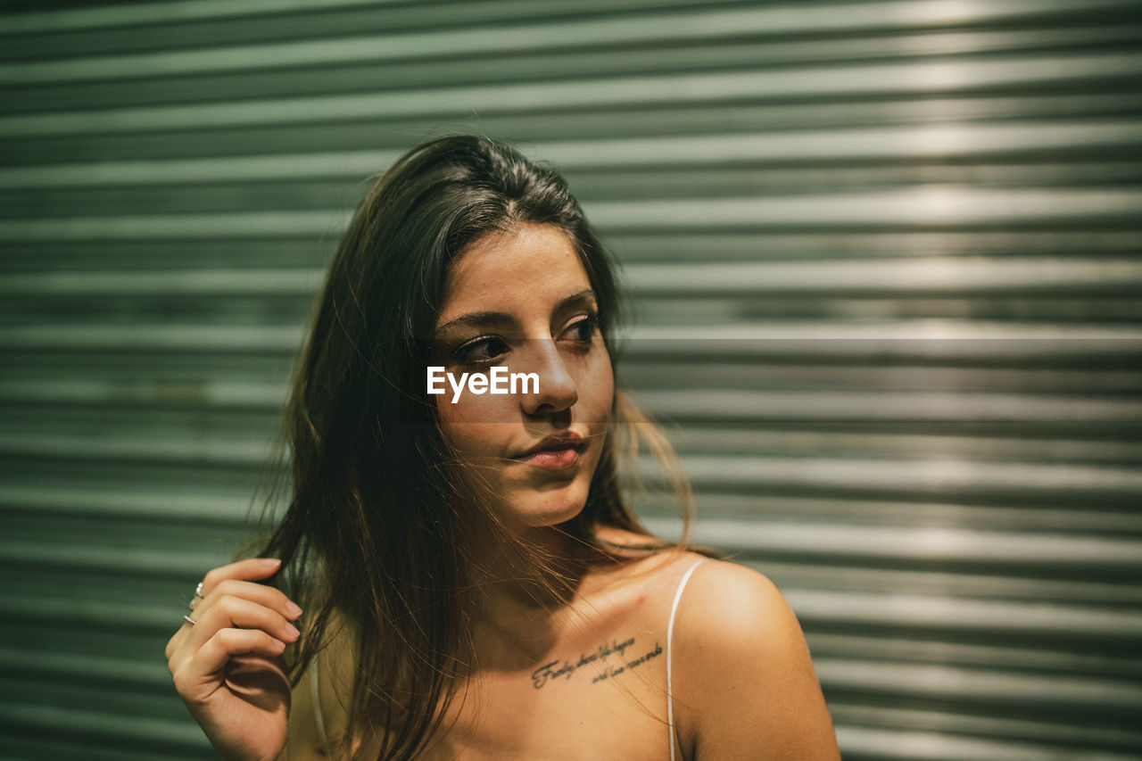 Beautiful young woman looking away against closed shutter