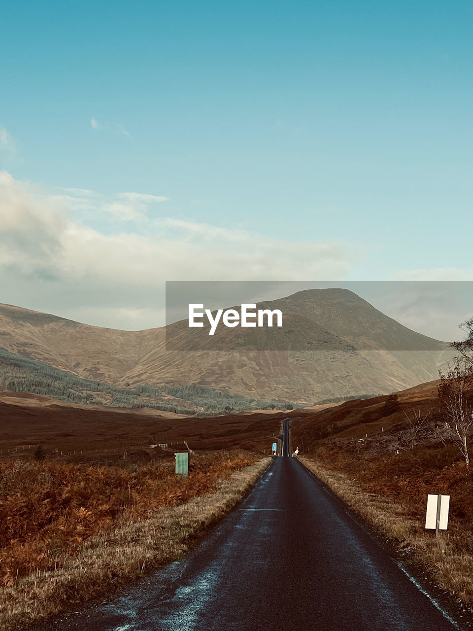 Empty road leading towards mountains against sky