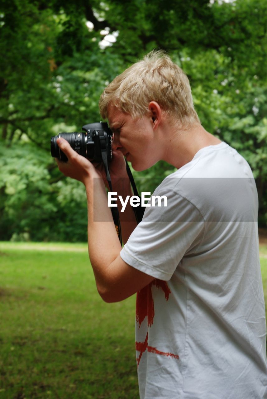 Side view of man holding camera on field