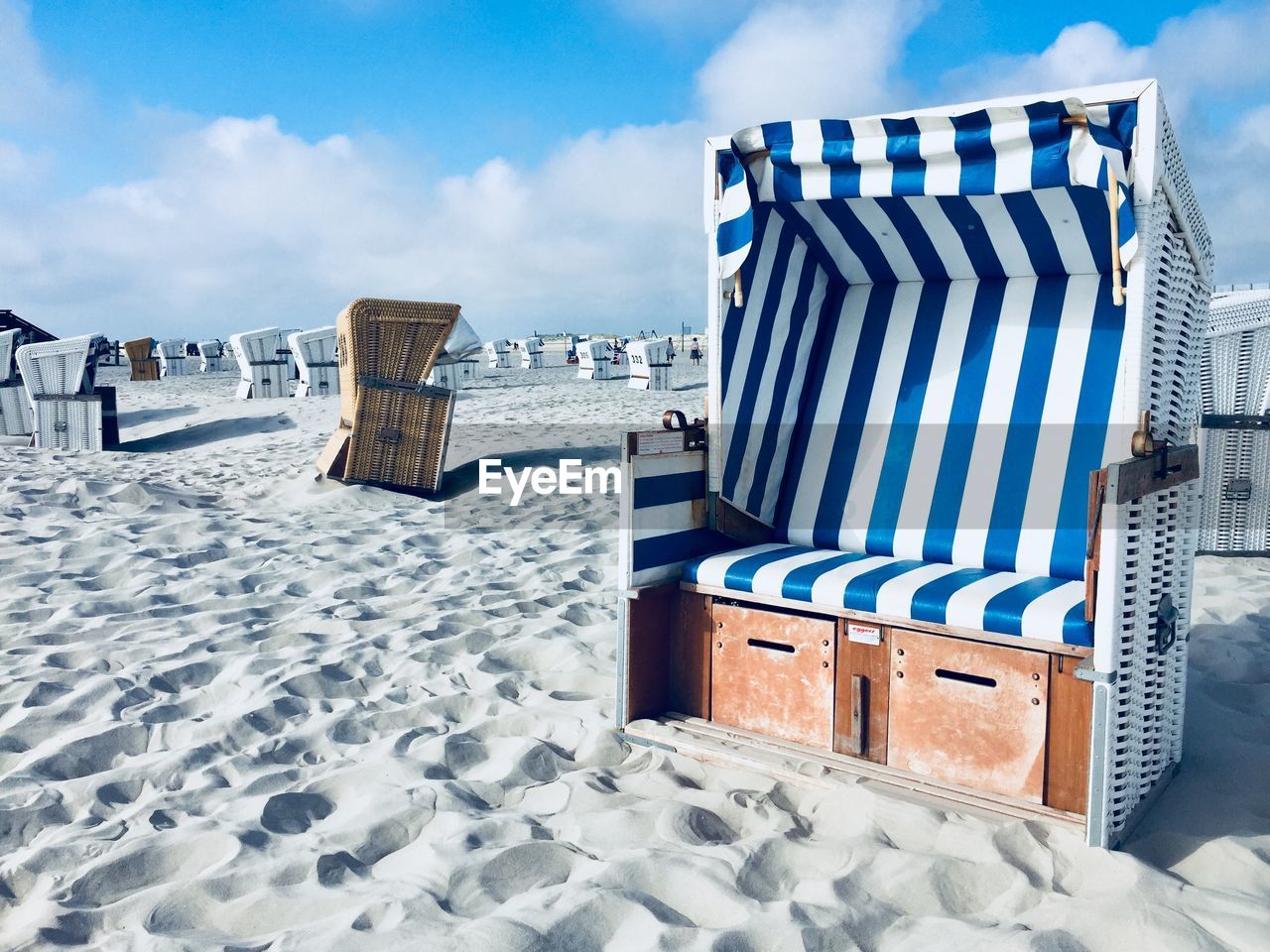 Hooded chairs on beach against sky