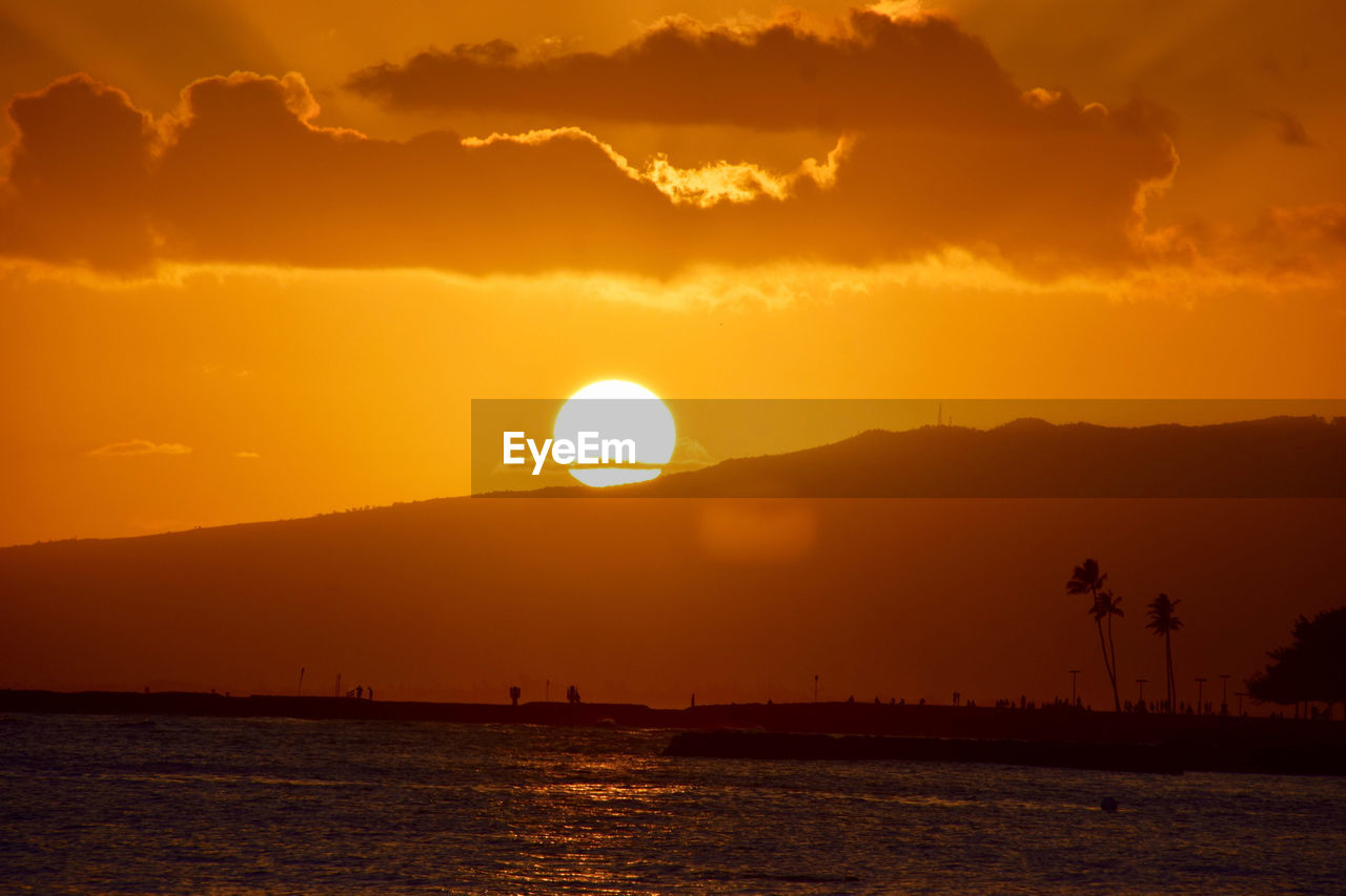Scenic view of sea and silhouette mountain against sky during sunset