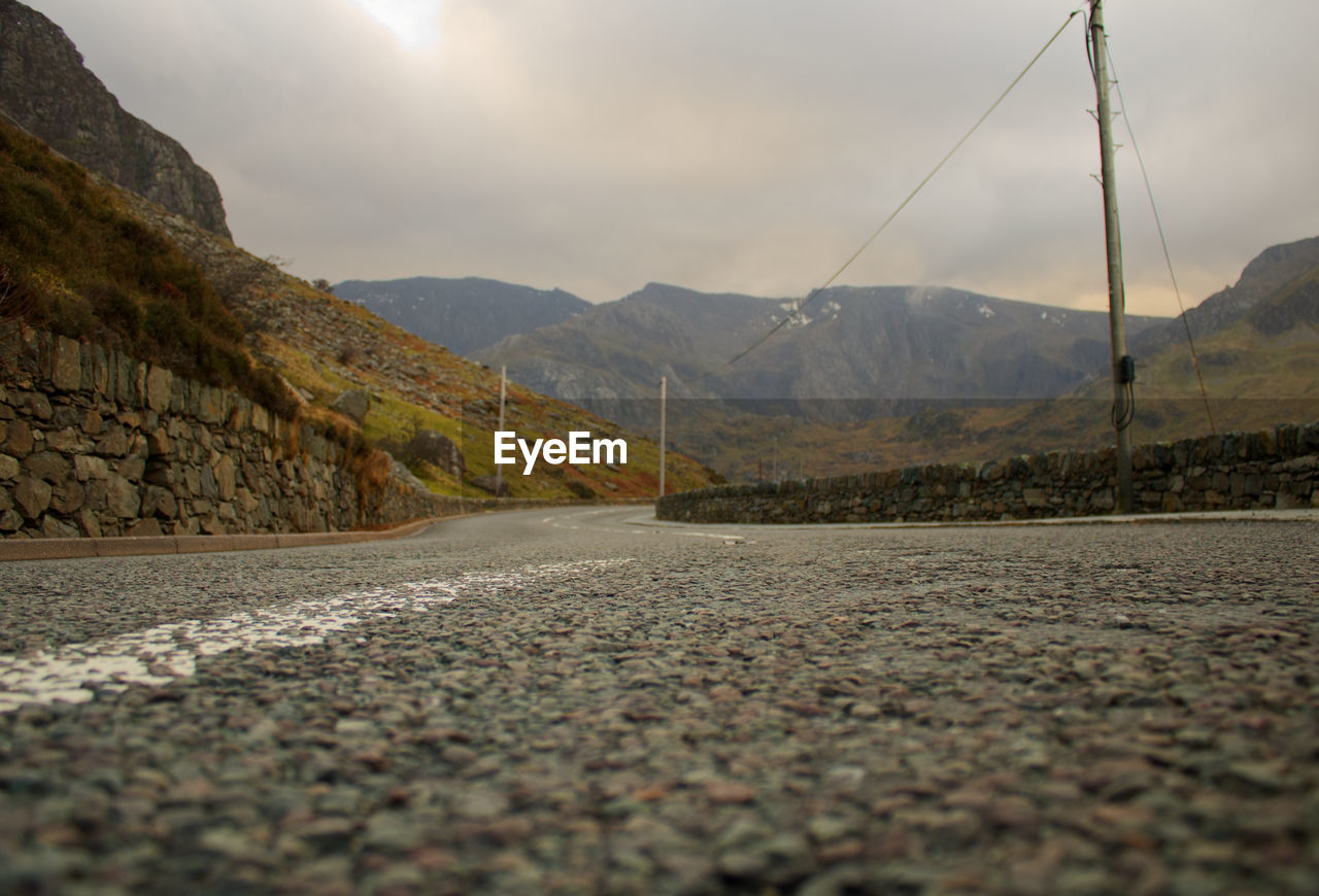 Surface level of road by mountains against sky