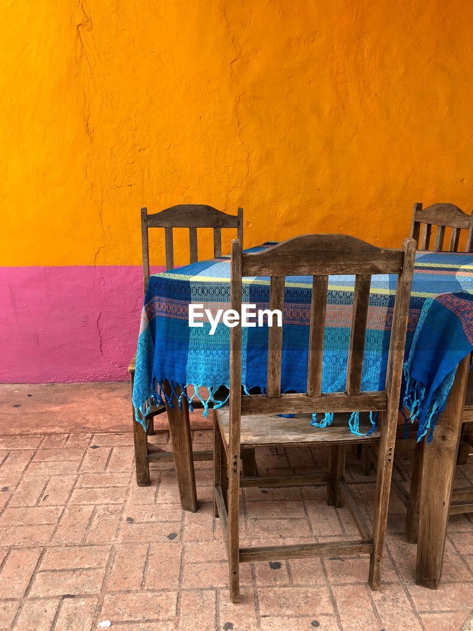 Empty chairs and table against yellow wall