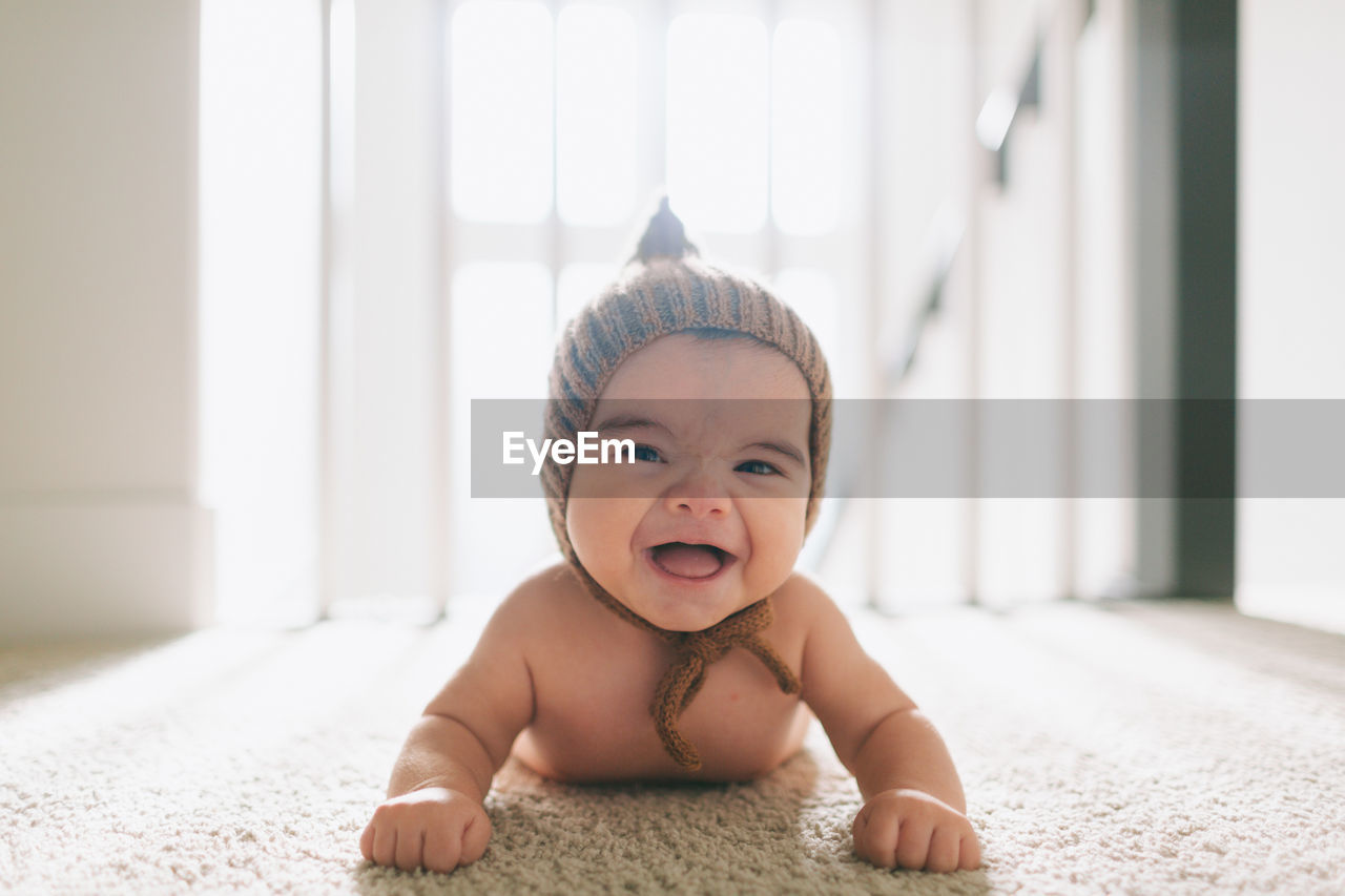 Portrait of cute baby boy on carpet at home
