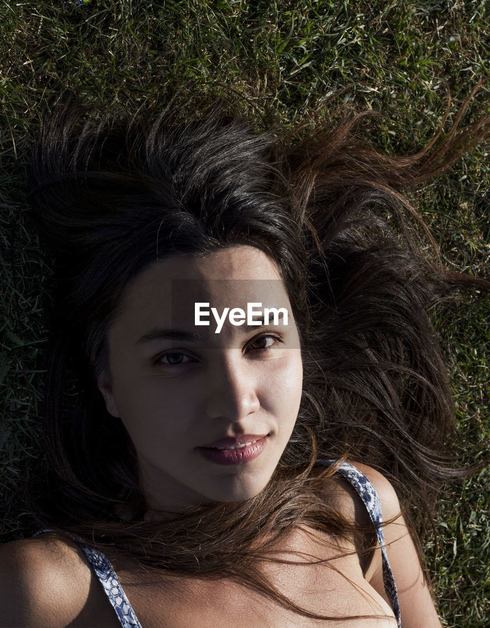 Portrait of young woman laying on grass, close up