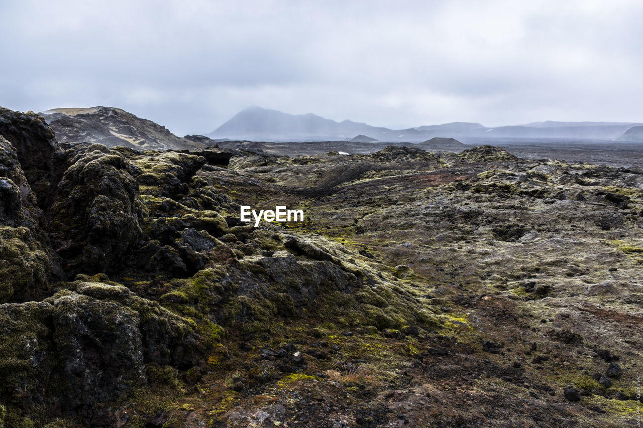 Scenic view of volcanic landscape against cloudy sky