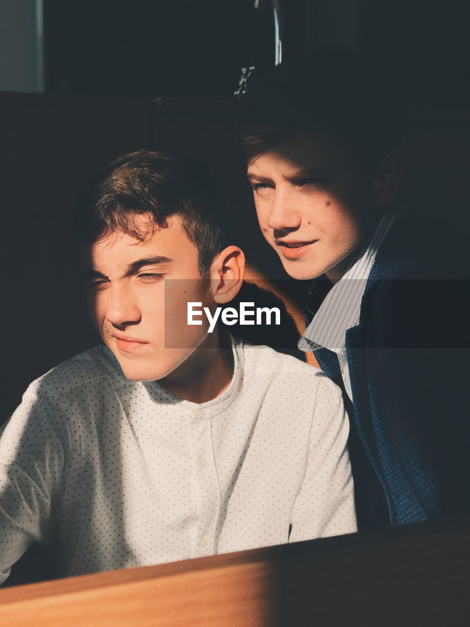 Close-up of young men looking away by wooden table