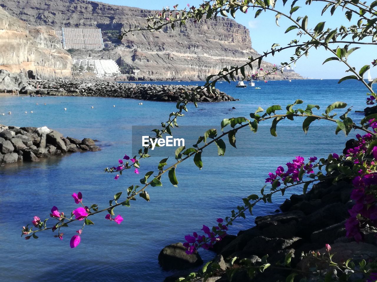 Scenic view of sea by rocks against sky