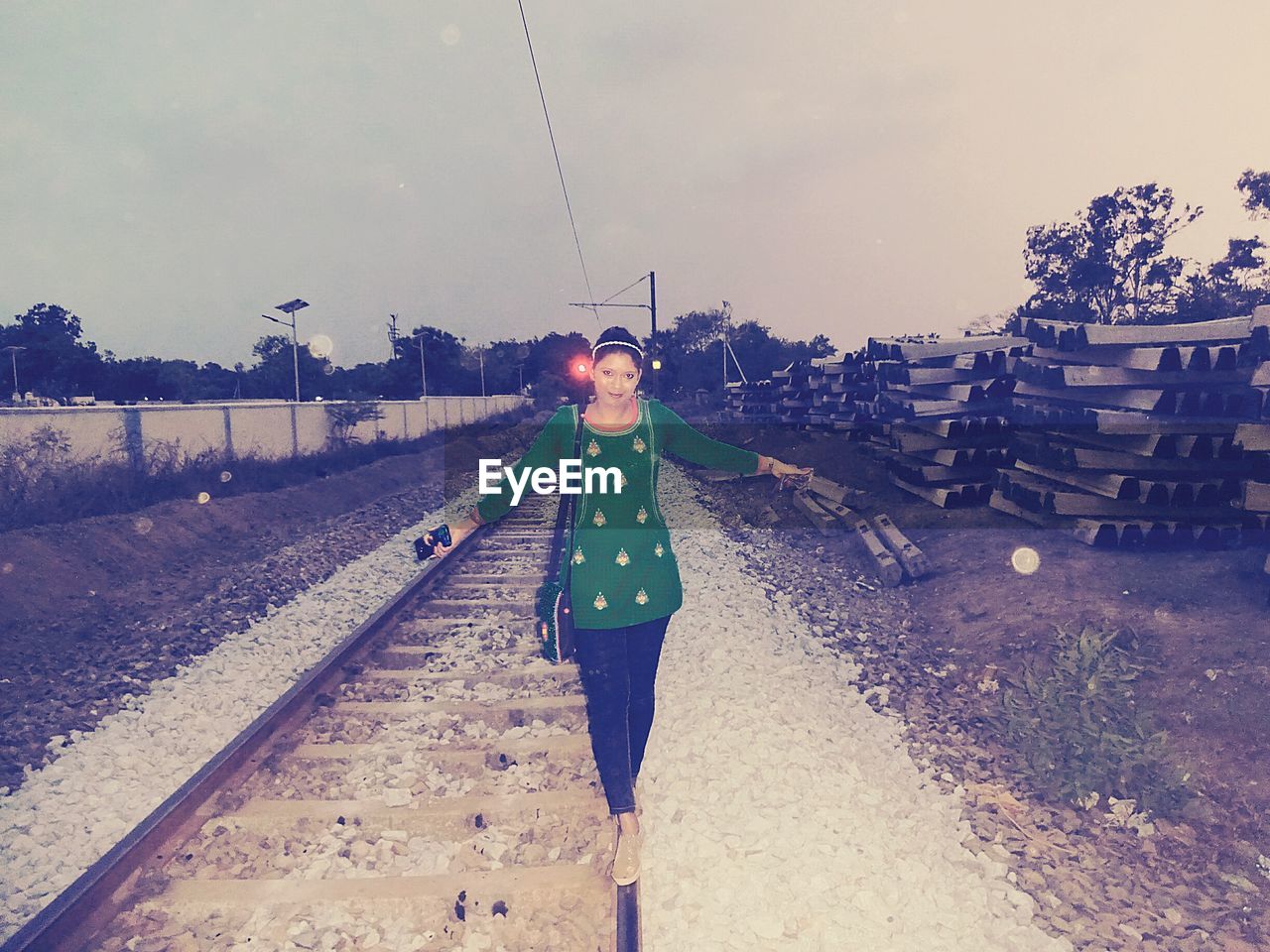 Portrait of woman walking on railroad track against sky