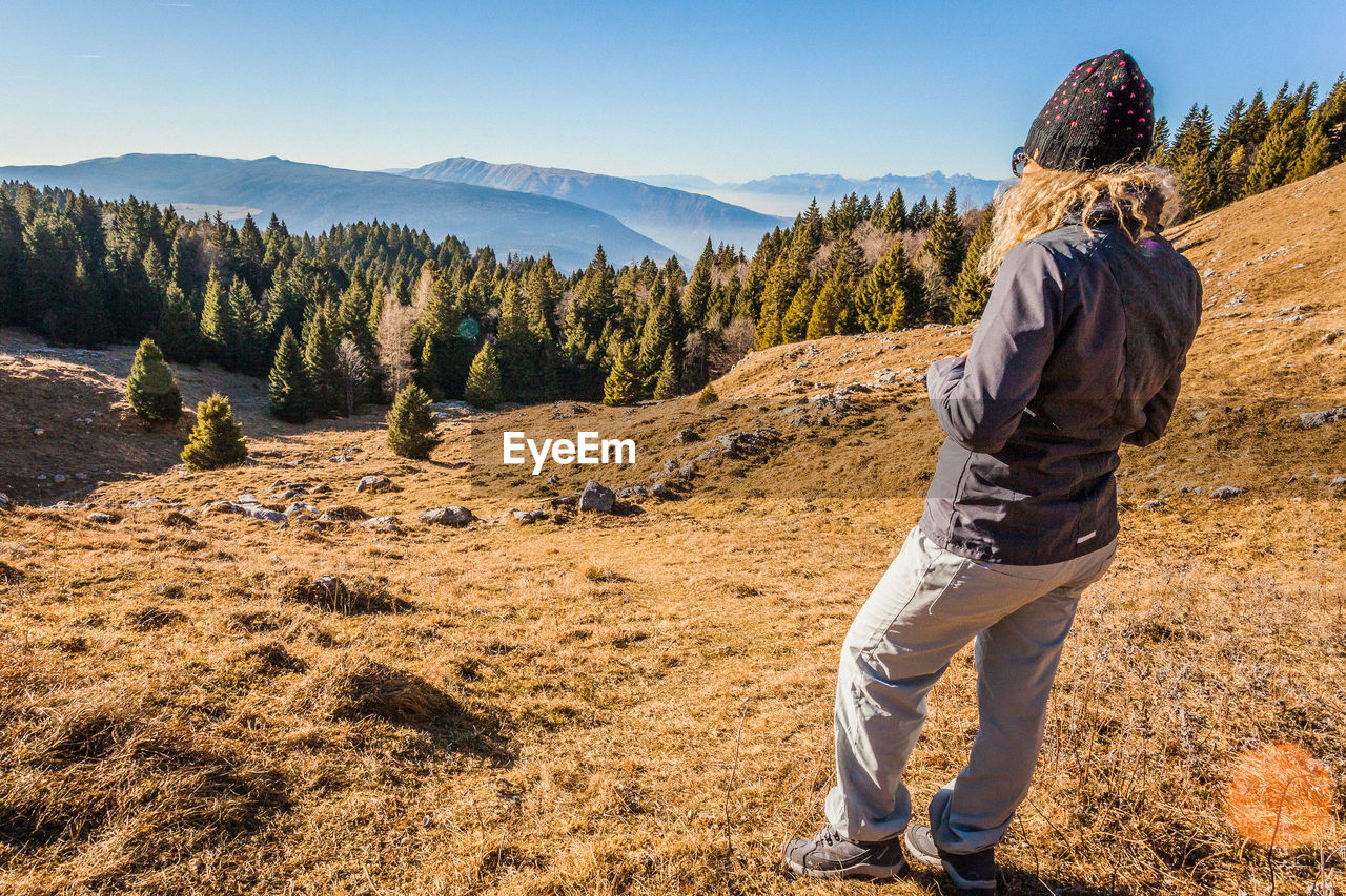REAR VIEW OF MAN LOOKING AT MOUNTAIN