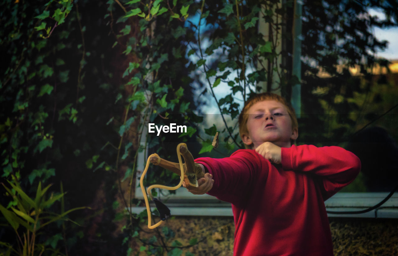 Boy playing with slingshot in yard