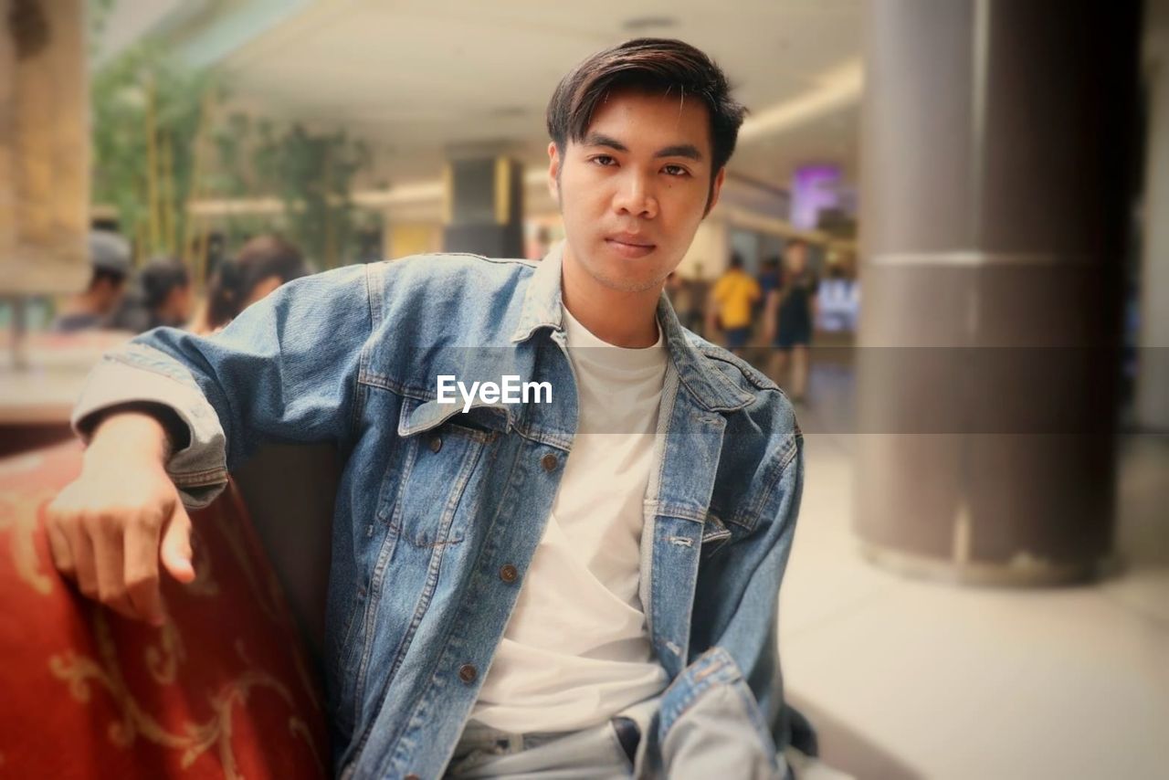 Portrait of good looking asian man sitting in department store 