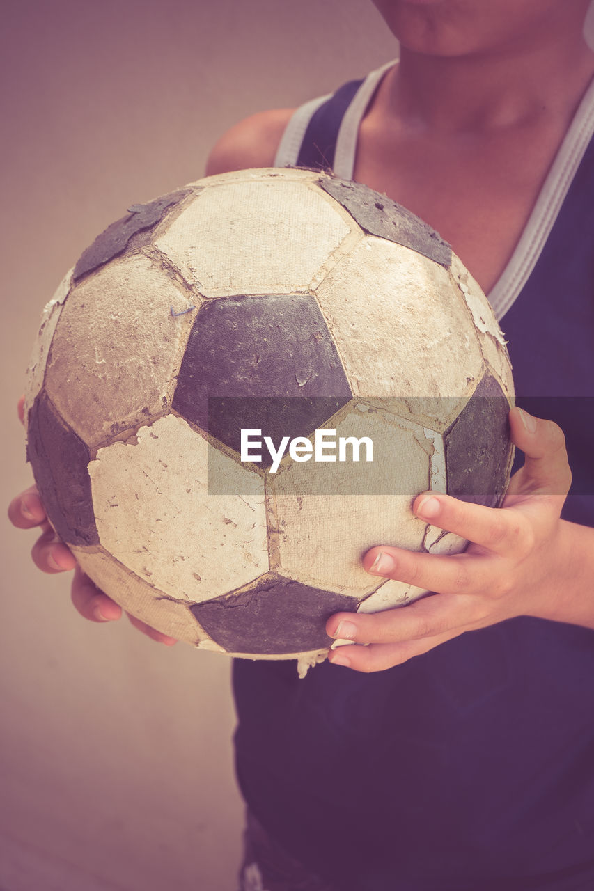 Close-up of boy holding football indoors