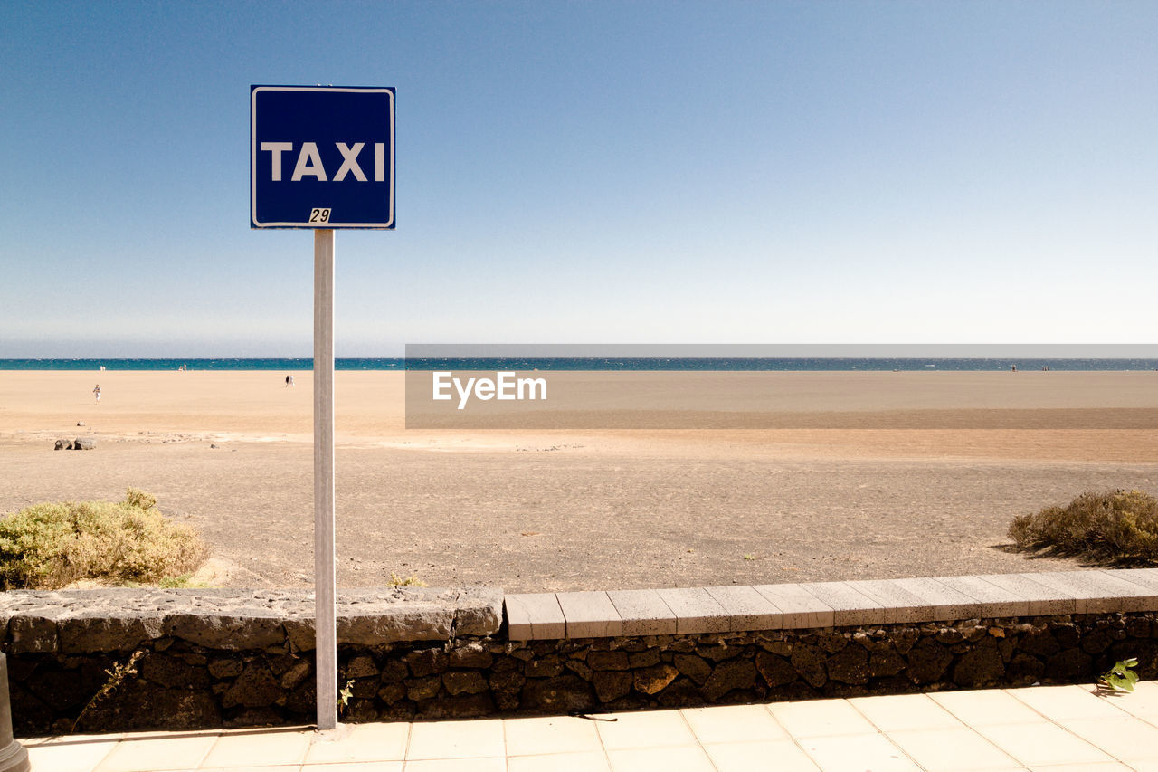 Information sign against beach and sky on sunny day