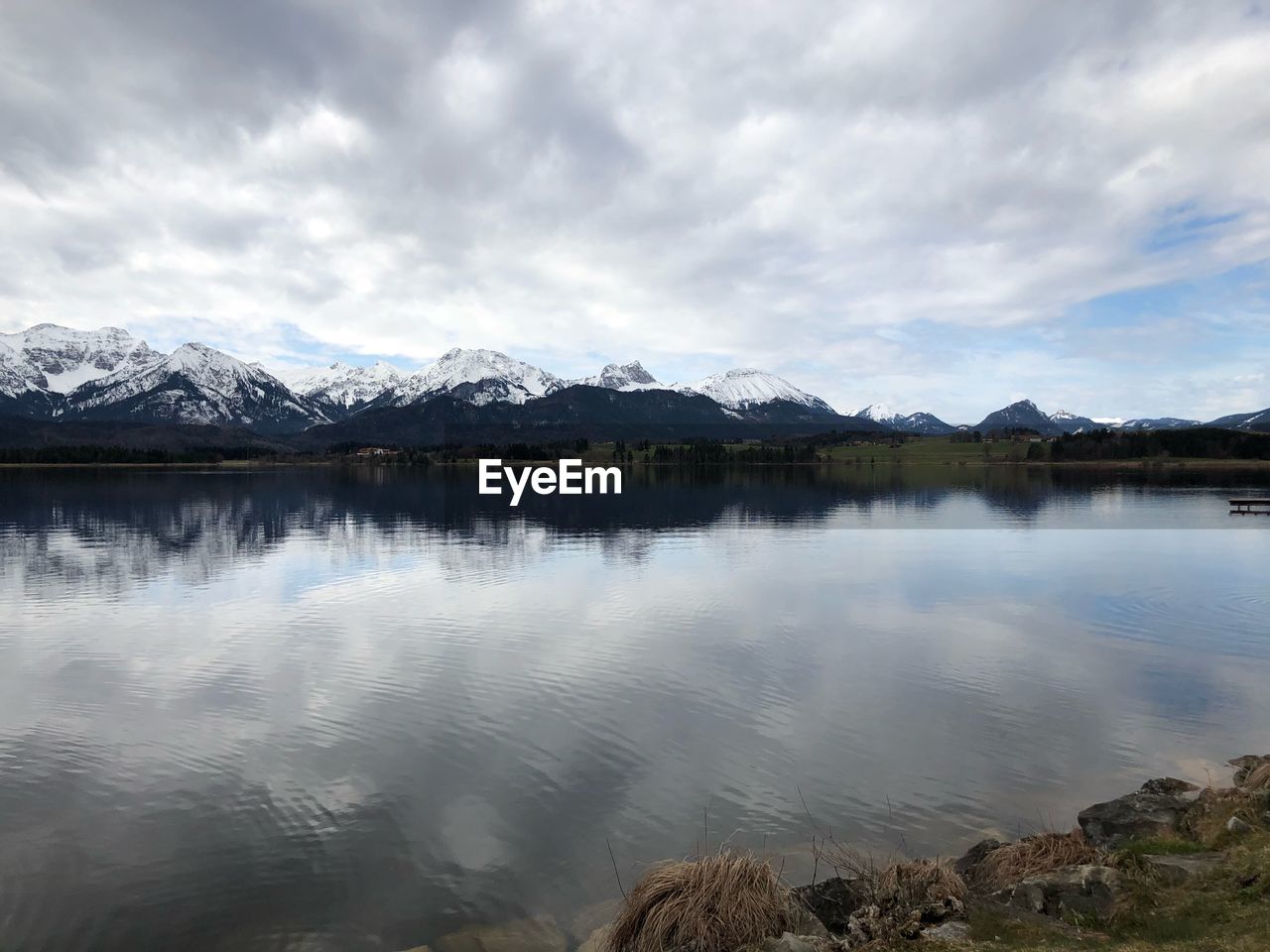 Scenic view of lake by snowcapped mountains against sky