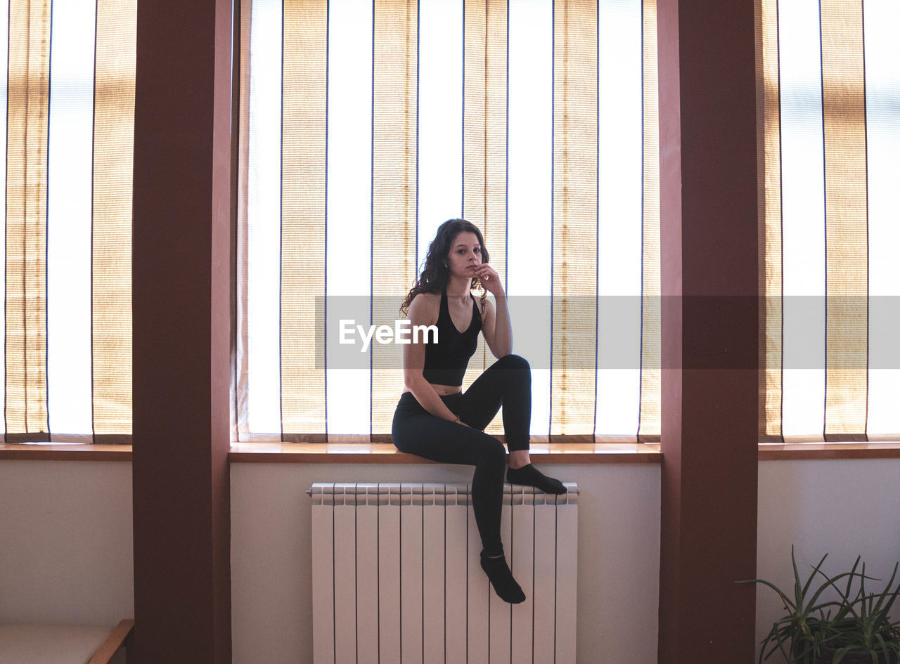 Thoughtful girl sitting on the windowsill