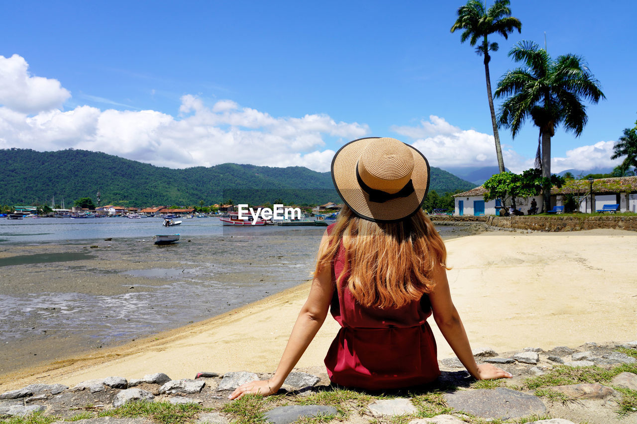 Tourist woman relax peaceful sitting on wall in tropical destination