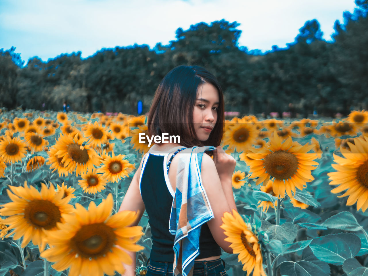 Portrait of woman standing amidst flowering sunflowers