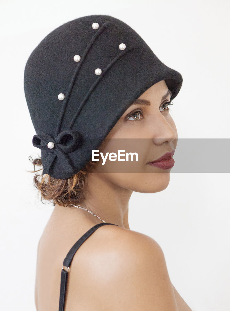 Close-up of smiling woman wearing hat against white background