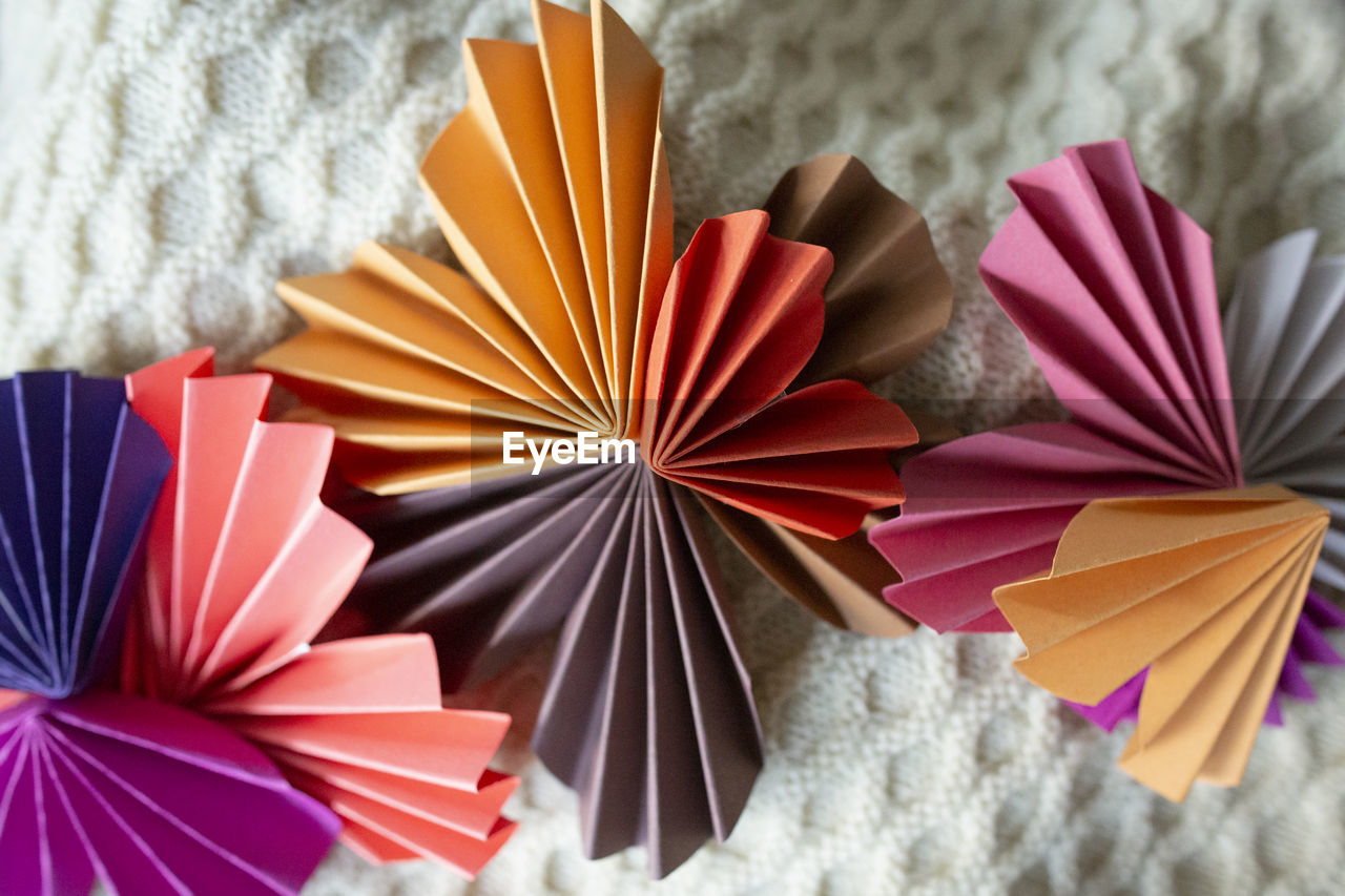 Colorful origami shapes arranged into design on knit fabric background