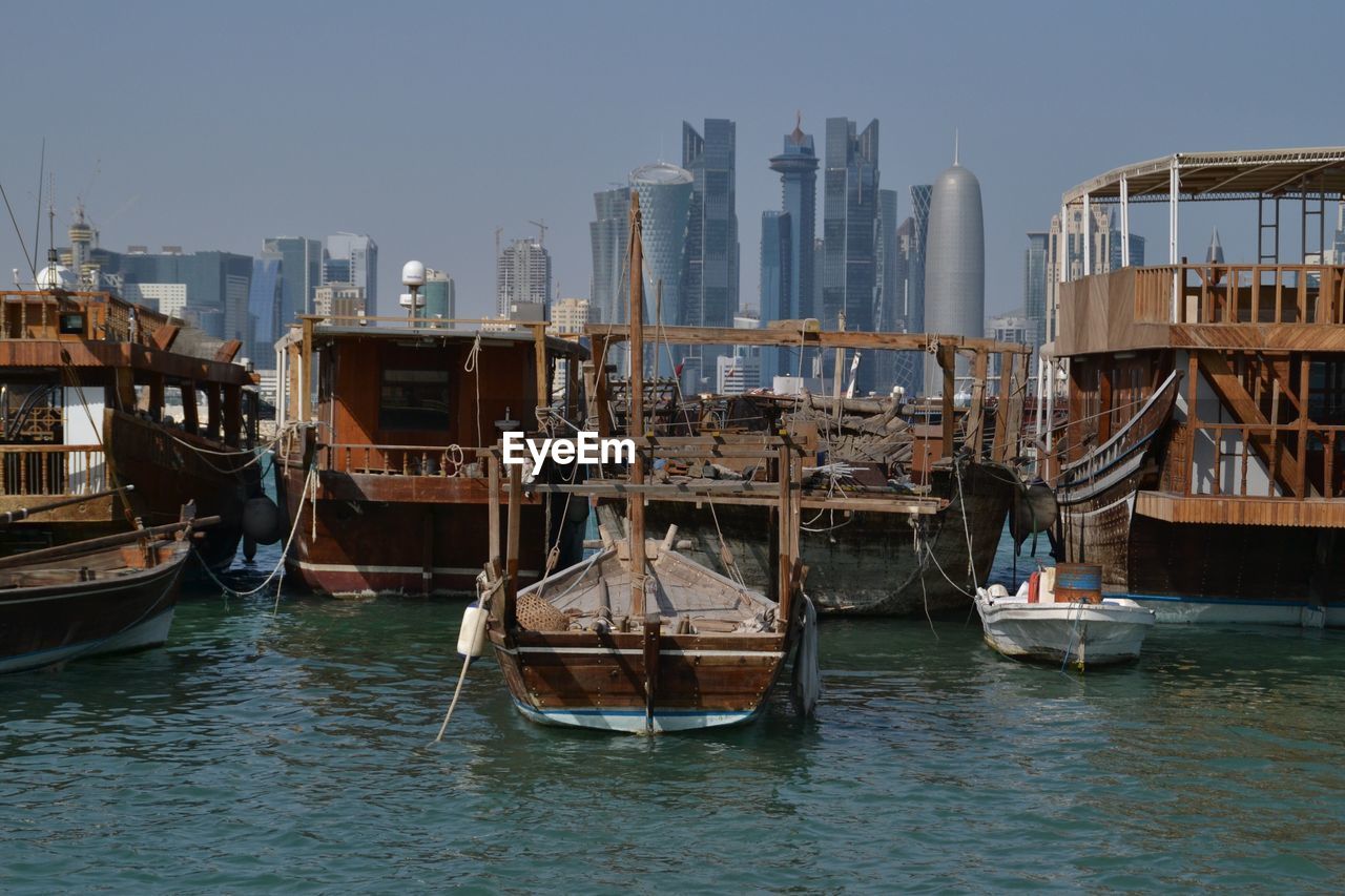 Boats moored at harbor against doha tower in city