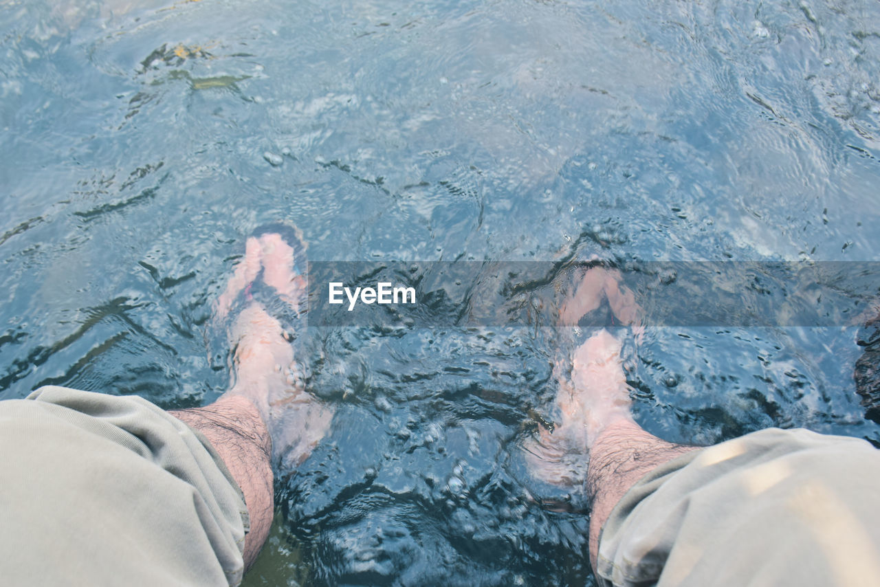 Low section of man relaxing in swimming pool