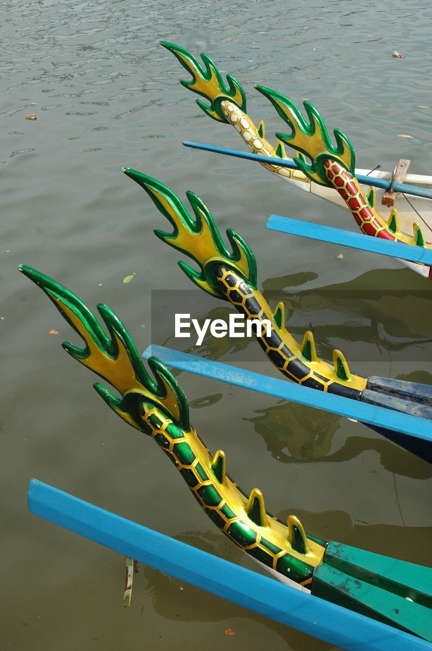 Artificial dragon tails on boats moored in river