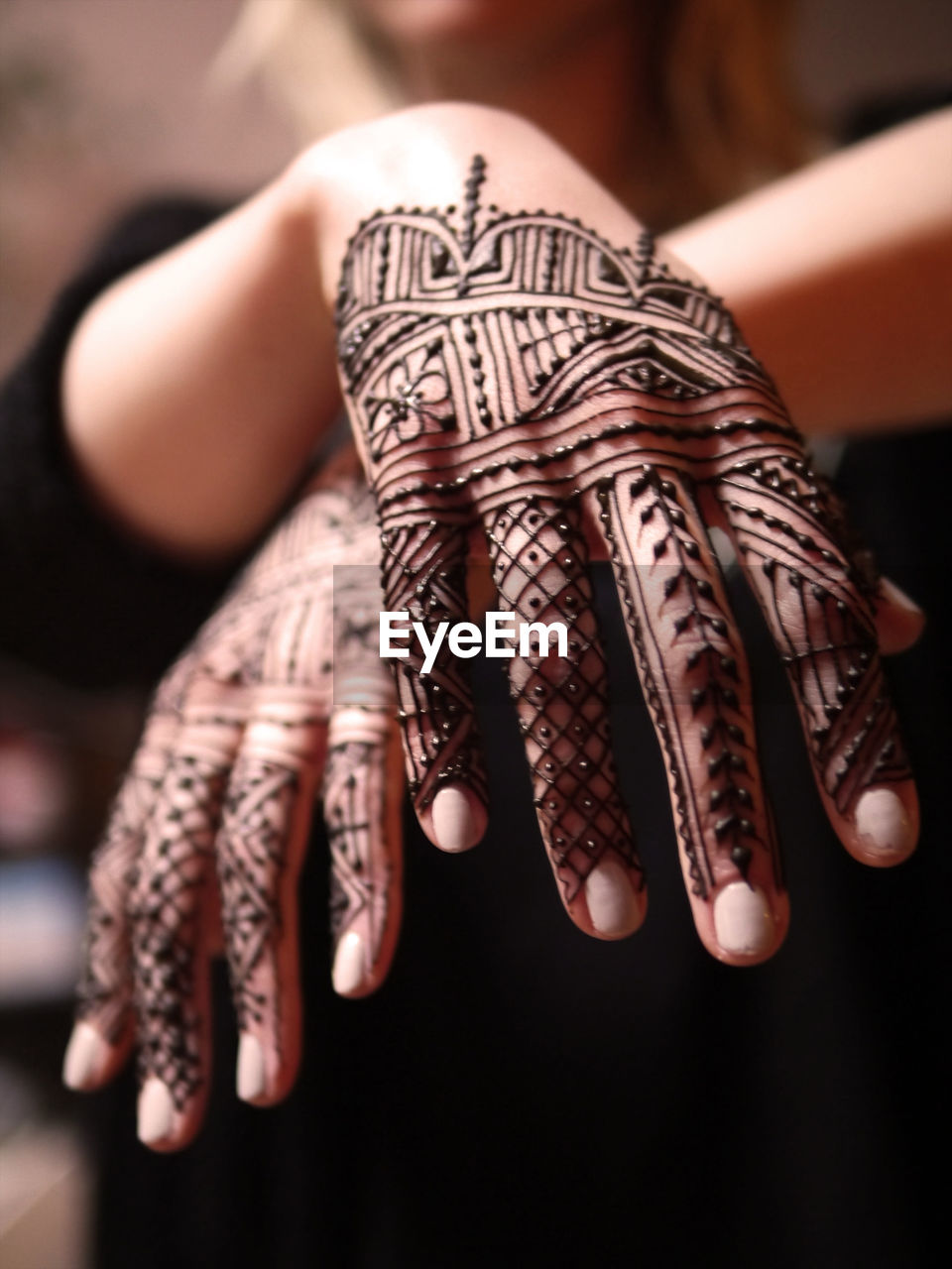 Midsection of woman with henna tattoos on hands