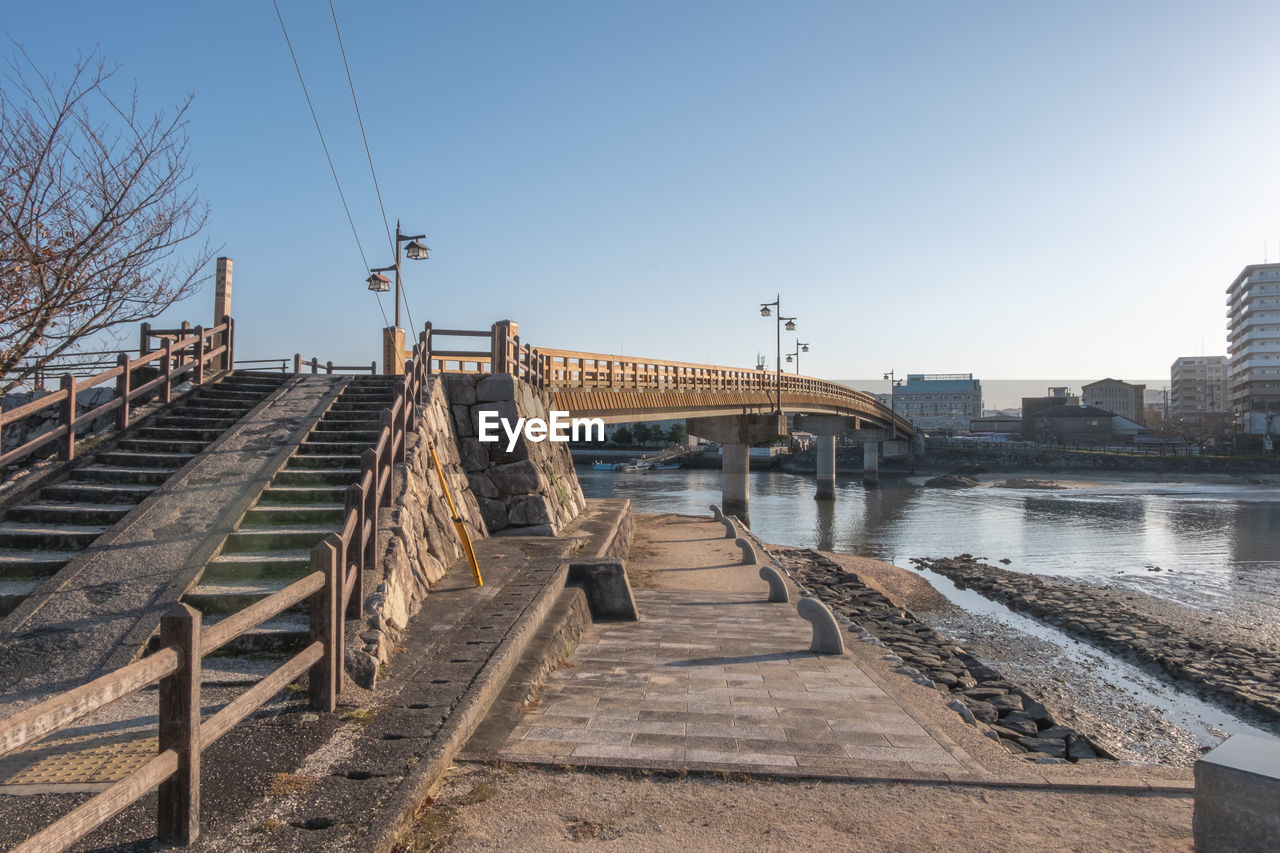 BRIDGE OVER RIVER BY BUILDINGS AGAINST SKY