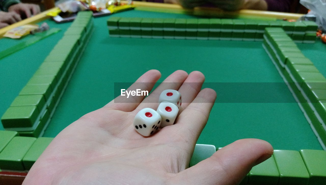 Cropped image of hand holding dices while playing mahjong