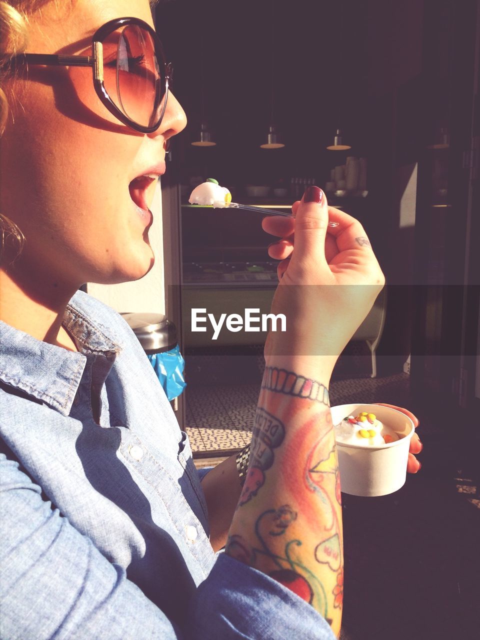 Side view of young woman eating ice cream outdoors