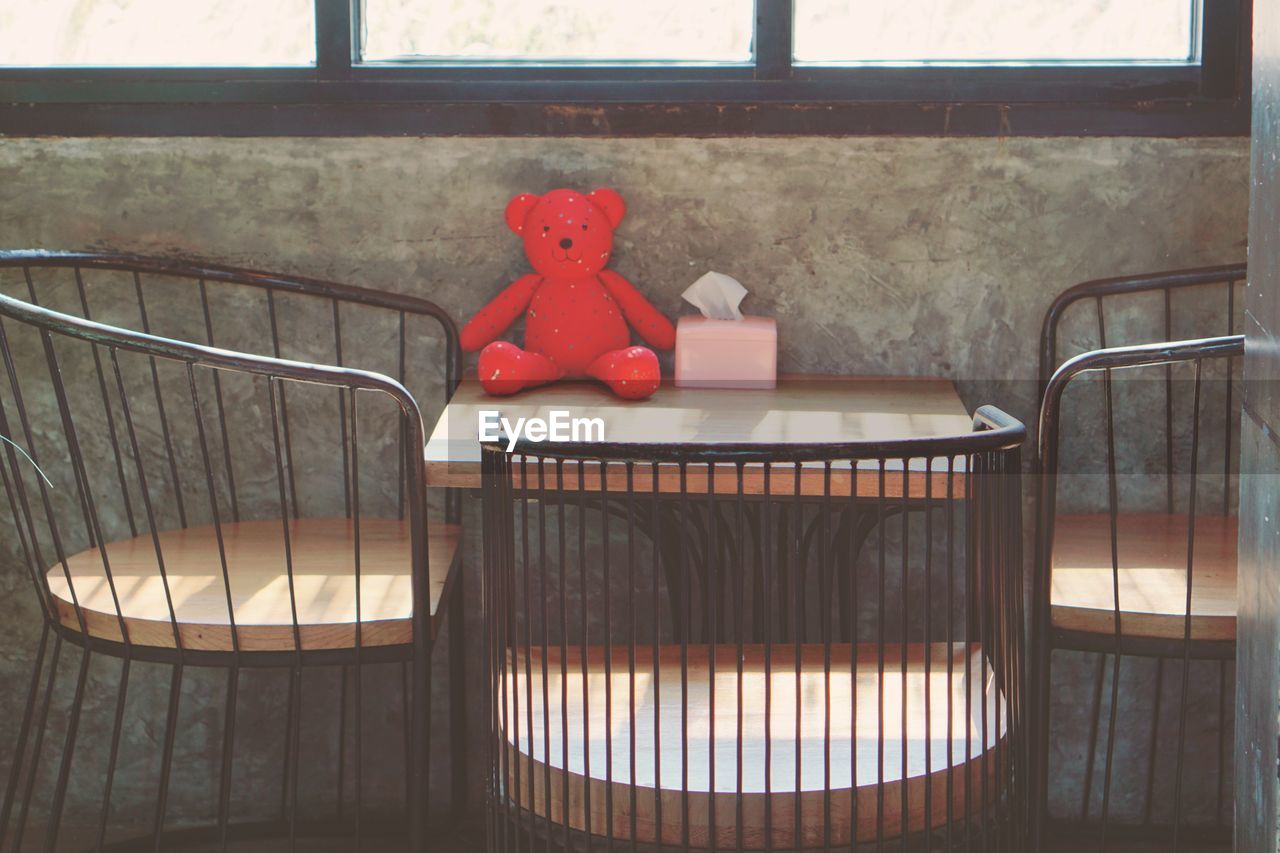 A teddy bear on the table in a coffee shop.
