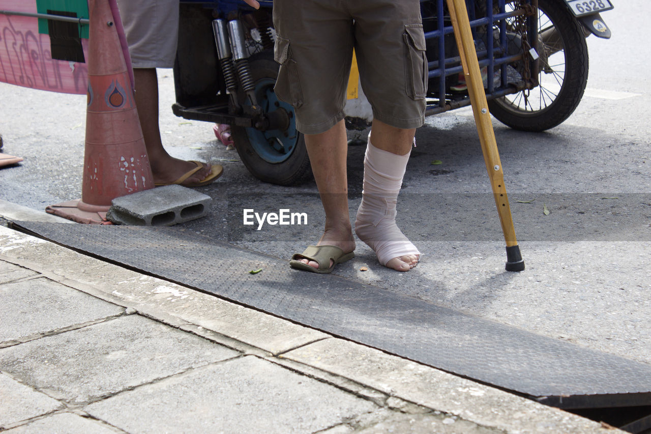 Low section of injured man walking on footpath