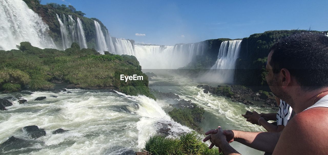 SCENIC VIEW OF WATERFALL AGAINST ROCKY COASTLINE